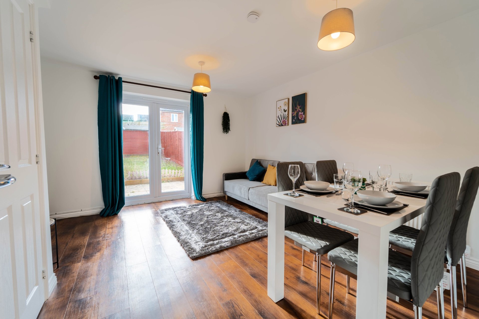 Open-plan living and dining area with wooden flooring, dining table, chairs, and seating area