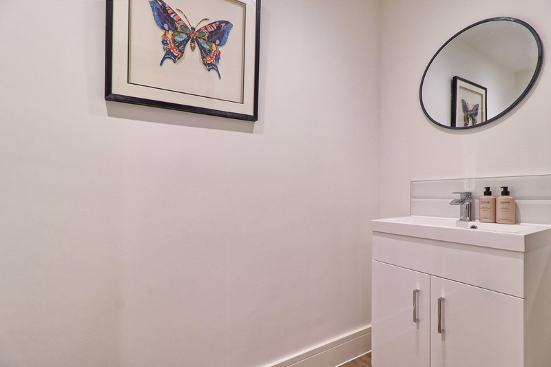 Modern bathroom with white vanity sink, mirror, and butterfly artwork on wall