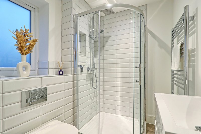 Modern bathroom with walk-in shower, white subway tiles, heated towel rail and window