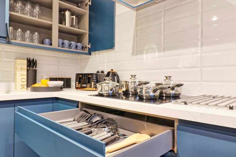 Modern kitchen with blue cabinetry, white countertop, stainless steel cookware and open drawer