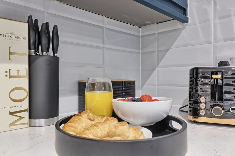 Modern kitchen counter with croissants, orange juice, fruit bowl and branded appliances