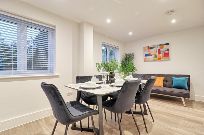 Modern dining area with white table, black chairs, built-in bench seating and large windows