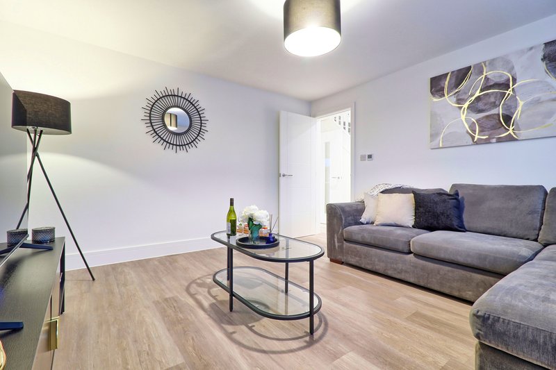 Modern living room with gray sofa, coffee table, wall clock and tripod lamp