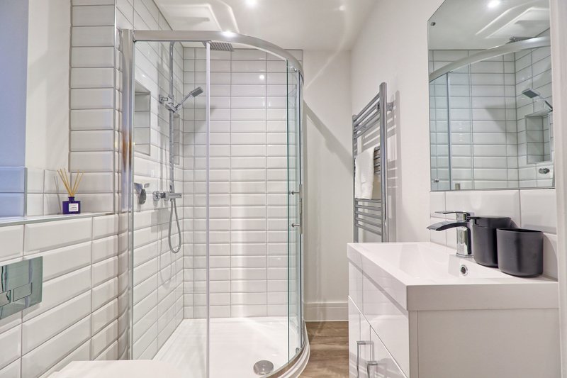 Modern bathroom with white subway tile, glass shower enclosure, white vanity and sink