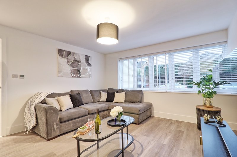 Modern living room with grey sectional sofa, coffee table, large windows and wooden flooring