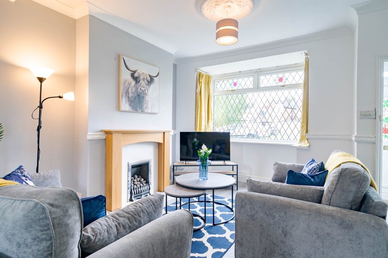 Bright living room with grey sofas, fireplace, TV, blue accents and large windows