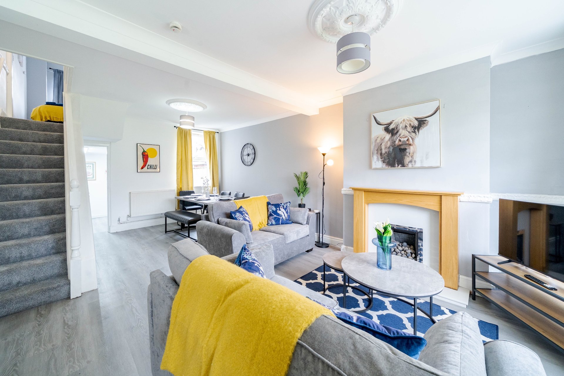 Modern living room with gray sofa, yellow accents, fireplace, and framed wall art