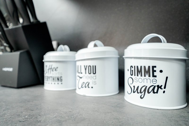 Kitchen counter with three white ceramic canisters with text labels and a knife block