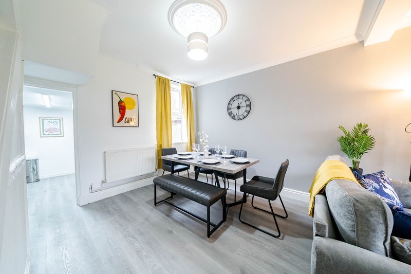 Modern dining area with black table, bench seating, yellow curtains and wall clock