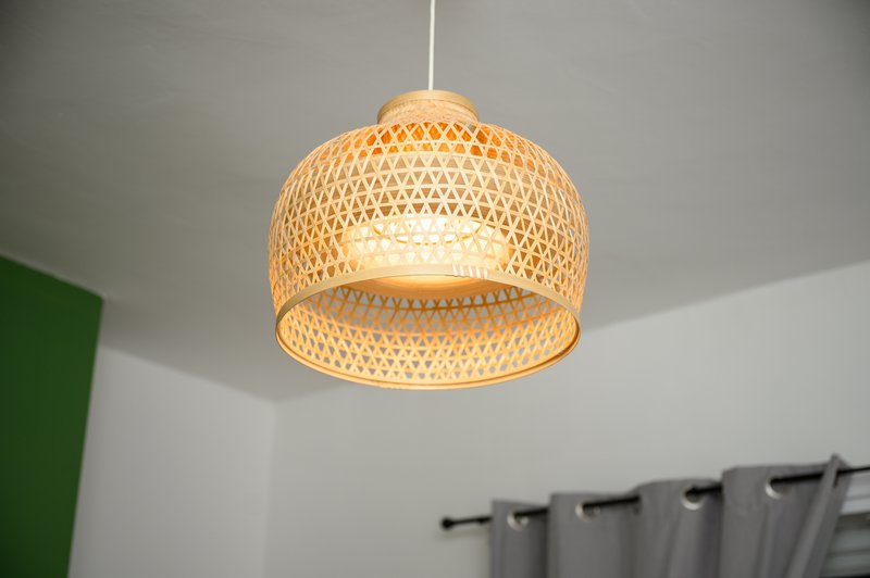 Woven rattan pendant lamp hanging from ceiling in bright room