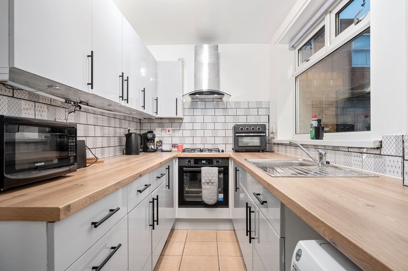 Modern kitchen with white cabinetry, wooden countertops, stainless steel appliances and subway tile backsplash