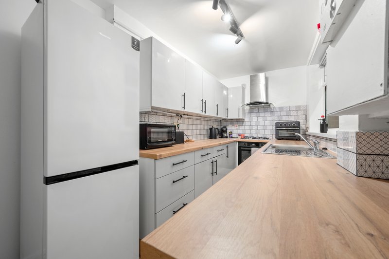 Modern kitchen with white cabinetry, wooden countertops, stainless steel appliances and track lighting