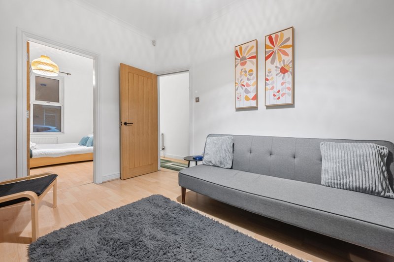 Living room with gray sofa, wooden doors, framed wall art, and gray area rug