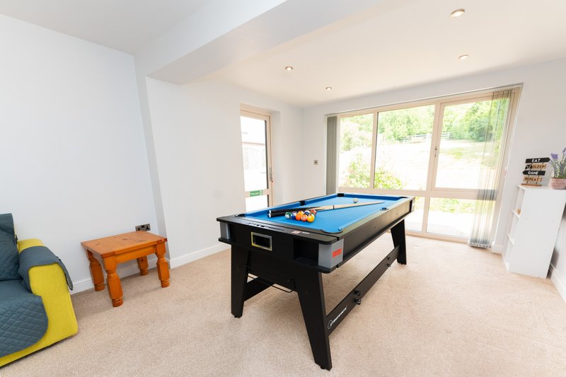 Spacious recreation room with pool table, seating area, and glass doors to garden