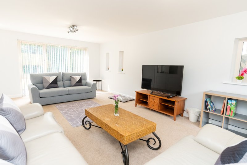 Bright living room with grey sofa, wooden TV stand, cork coffee table and comfortable seating