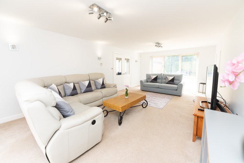 Spacious living room with cream corner sofa, wooden coffee table, and grey armchair