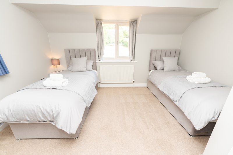 Twin bedroom with two single beds, white bedding, wooden floor and window