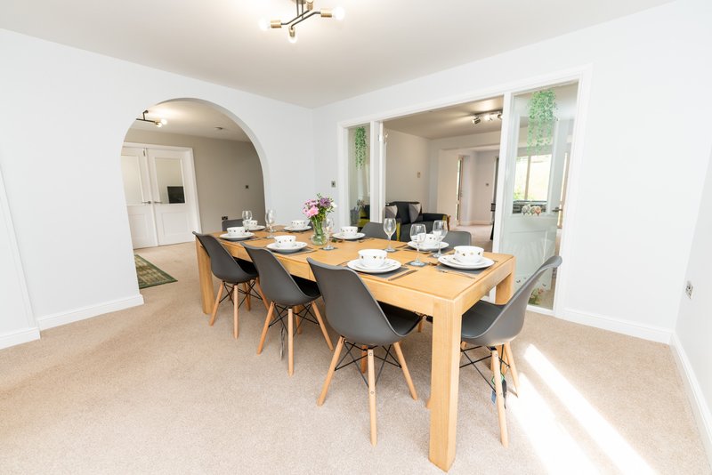 Dining room with wooden table, black chairs, and kitchen visible through archway