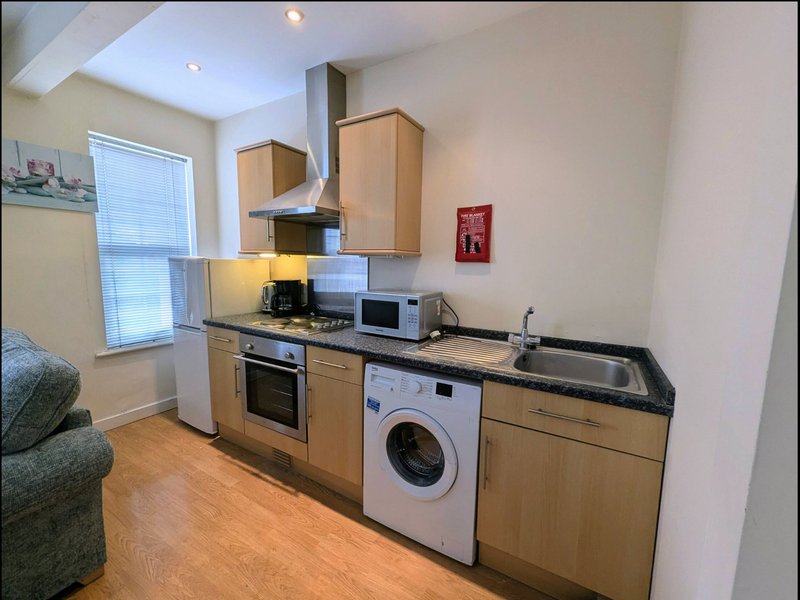 Modern kitchen with wooden cabinets, stainless steel sink, built-in oven, and washing machine