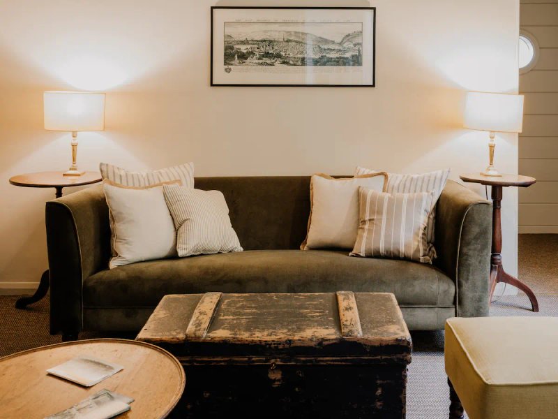 Living room with dark leather sofa, patterned cushions, wooden coffee table and side lamps