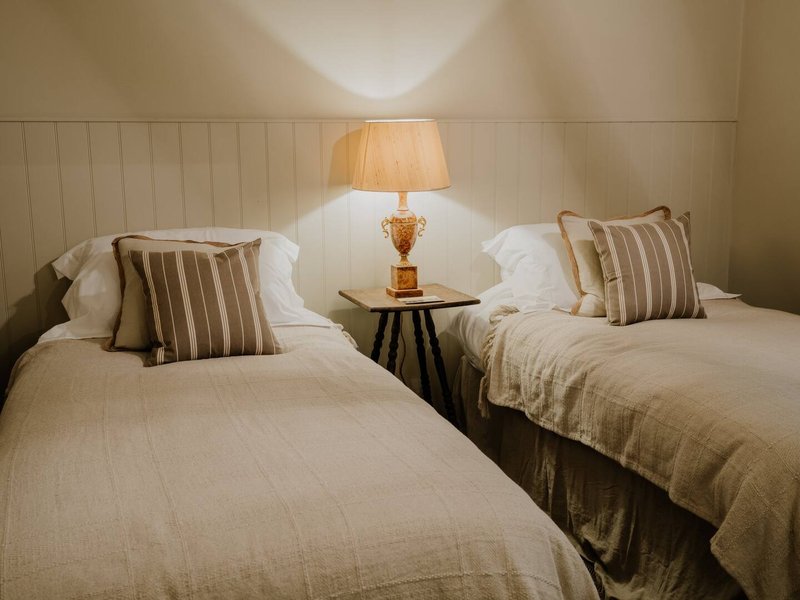 Twin bedroom with two beds, striped cushions, bedside lamp and neutral décor