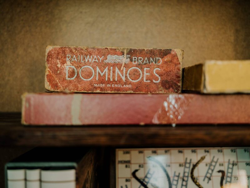 Vintage Railway Brand dominoes box on shelf with books and decorative items