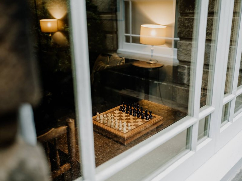 Cozy seating area with chess board, candles, and wicker chair by window