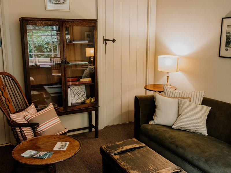 Living room with dark sofa, wooden chair, display cabinet, coffee table and side lamp