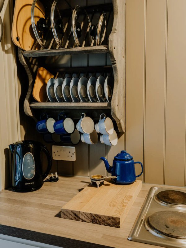 Kitchen storage wall with dishes, cookware, kettle, and small appliances organized on shelves