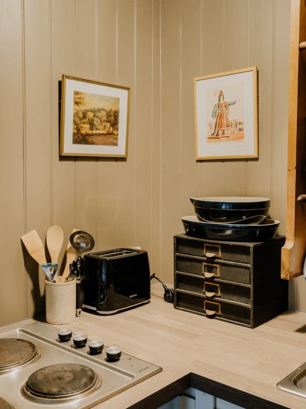 Kitchen counter with cooking utensils, black appliances, and framed artwork on beige wall