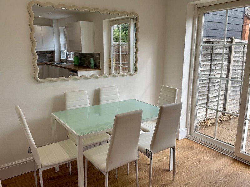 Dining area with mint green table, four cream chairs, decorative mirror, and French doors to patio