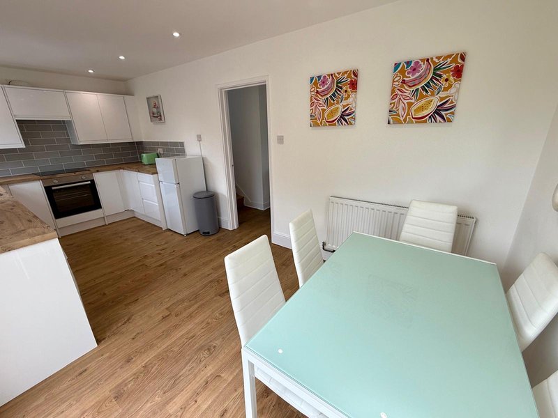 Open-plan kitchen and dining area with white cabinetry, dining table, and colorful wall art