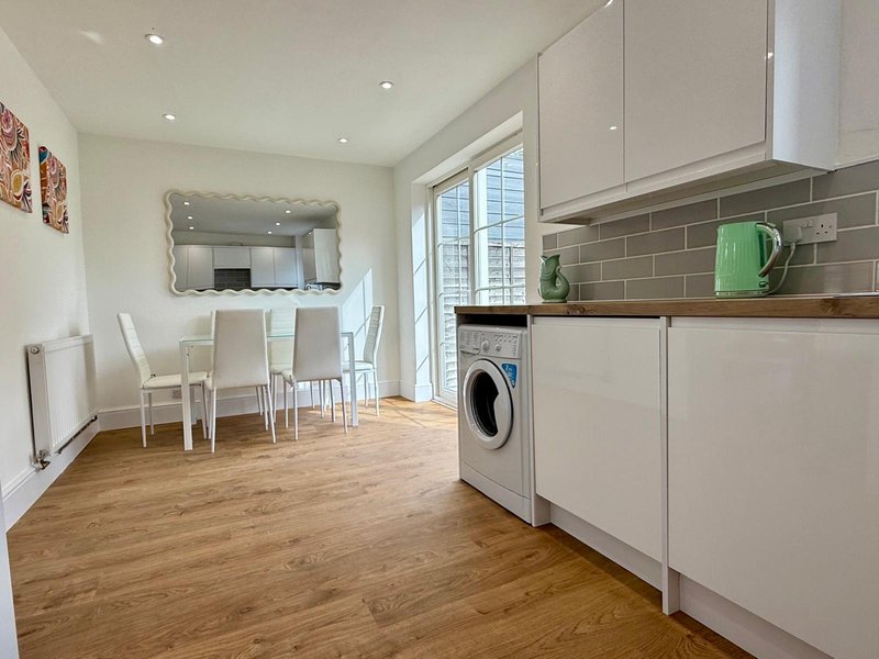 Open-plan kitchen and dining area with white cabinetry, wooden worktops, dining table and chairs