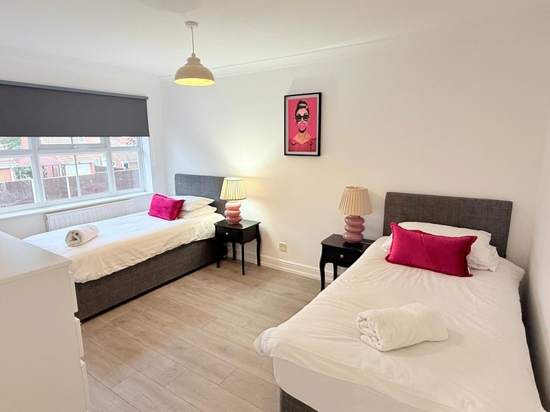Bright bedroom with two single beds, wooden floor, pendant light and window seating area
