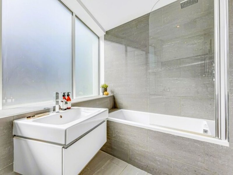 Modern bathroom with white vanity sink, glass shower enclosure, and frosted window