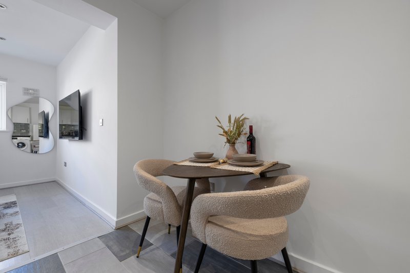 Dining nook with two upholstered chairs, small wooden table, and wall-mounted mirror