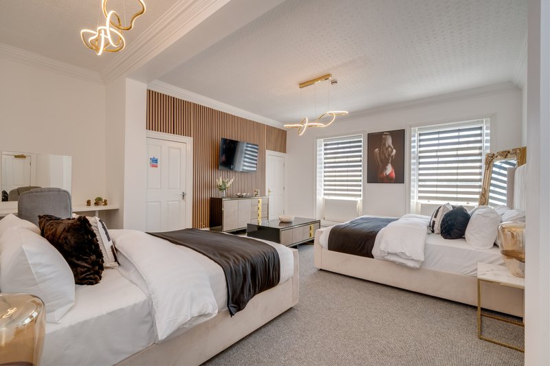 Modern bedroom with two beds, white bedding, wooden accents and pendant lighting