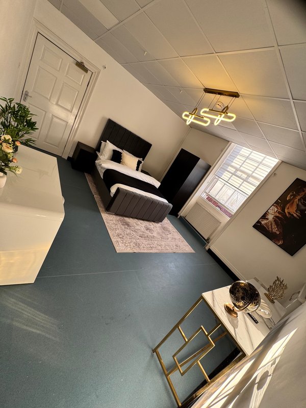 Modern bedroom with black and white furniture, teal flooring, pendant light and window