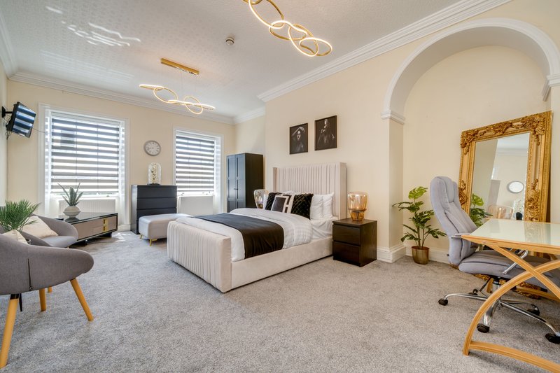 Spacious bedroom with double bed, seating area, mirror, and modern lighting fixtures