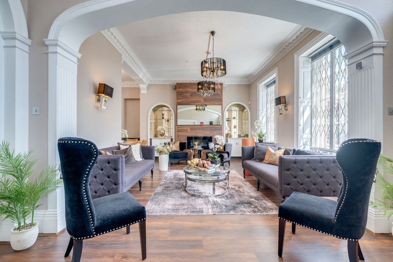 Spacious living room with fireplace, elegant furnishings, arched doorways, and natural light