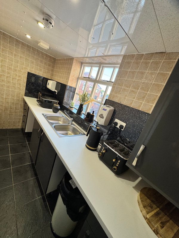 Modern kitchen with white countertop, black appliances, sink and window