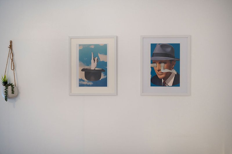 White wall with two framed artworks and decorative hanging plant