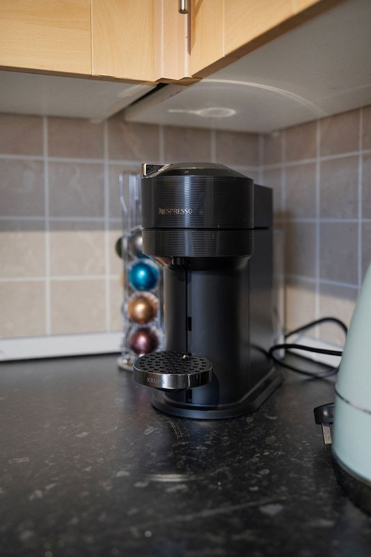Kitchen counter with black single-serve coffee maker and capsule holder