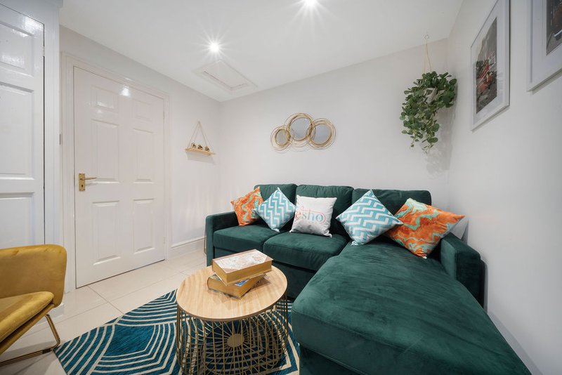 Modern living room with green sofa, colorful cushions, wooden table and yellow armchair