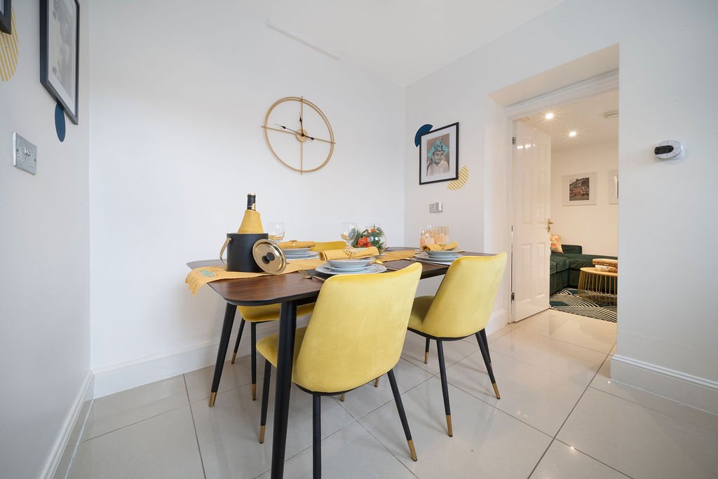 Modern dining area with yellow chairs, wooden table, and bottle of champagne on display
