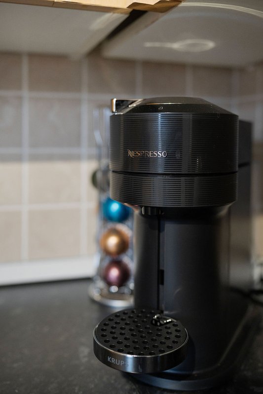 Modern kitchen counter with black Nespresso coffee machine and colorful capsule pod holder