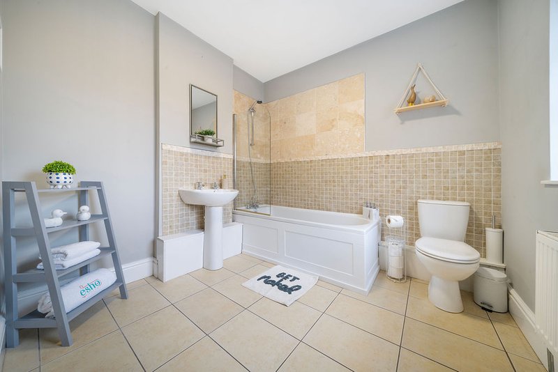 Modern bathroom with bath, shower enclosure, pedestal sink, toilet and beige tile walls