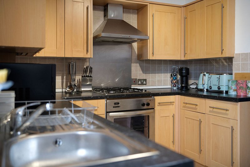 Modern kitchen with wooden cabinets, stainless steel appliances, black countertop and tiled backsplash