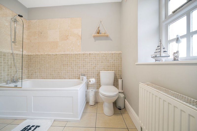 Bathroom with bathtub, toilet, sink, tiled walls and large window