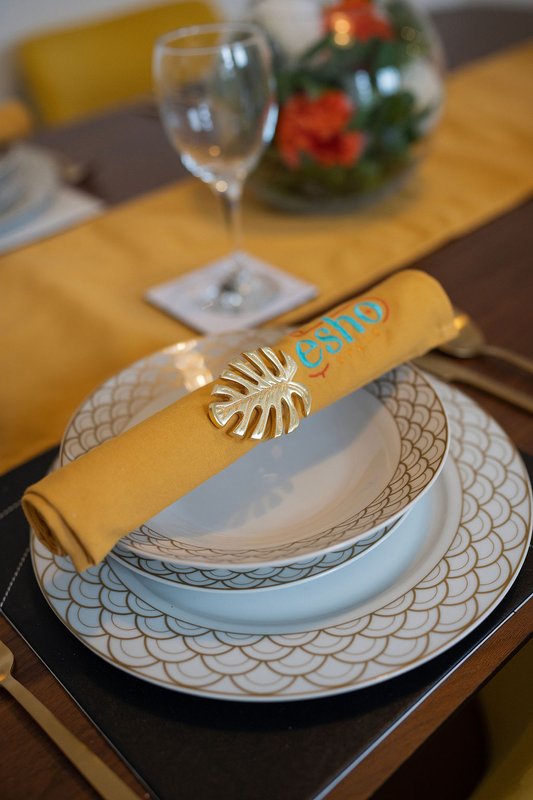 Formal dining table setting with stacked plates, napkin ring, and glassware